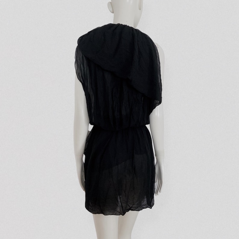 May include: A black, one-shoulder dress with a draped neckline and a cinched waist. The dress is made of a lightweight, semi-sheer fabric. The dress is displayed on a mannequin against a white background.