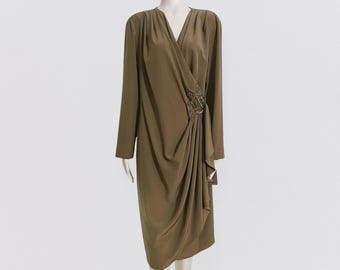 May include: A long-sleeved, olive green wrap dress with a gathered skirt and a large, jeweled embellishment at the waist.