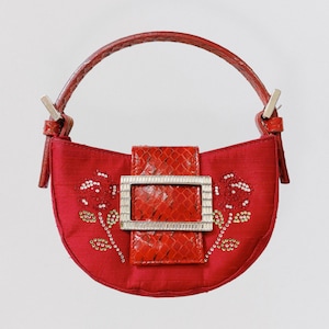 Peut inclure: Un sac à main rouge avec une boucle argentée et des broderies florales. Le sac à main a une poignée supérieure et une fermeture à rabat.