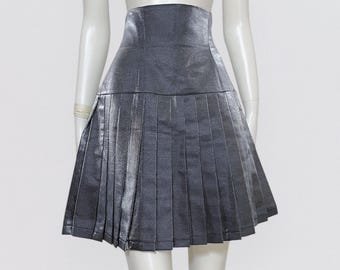 May include: A silver pleated skirt with a high waistline. The skirt is made of a shiny, metallic fabric.
