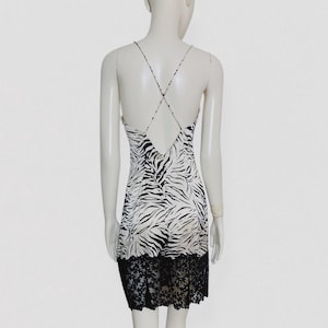 Peut inclure: Robe à bretelles blanche et noire à imprimé zébré, dos nu. La robe présente une bordure en dentelle noire. La robe est présentée sur un mannequin.