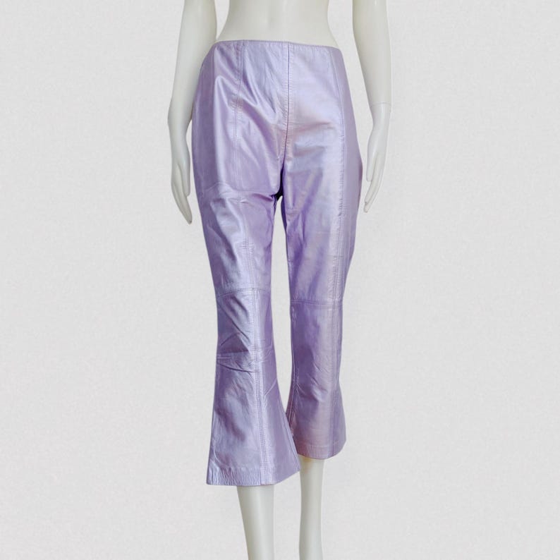 May include: Lilac-colored, cropped leather pants with a slight flare at the hem. The pants have a high waist and are displayed on a mannequin. The leather has a subtle sheen, giving the pants a polished look. The pants are a unique fashion statement.