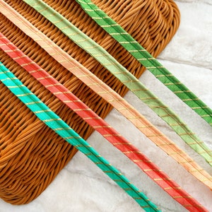May include: Five different colored ribbons with gold stripes. The ribbons are arranged in a row, with the green ribbon at the top and the orange ribbon at the bottom.