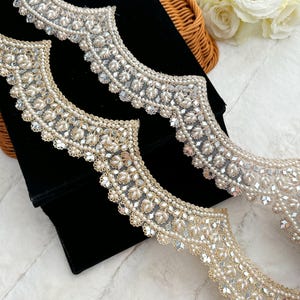 Puede incluir: Dos piezas de ribete de cuentas con un borde festoneado. El ribete está hecho de una tela transparente con pequeñas cuentas redondas y lentejuelas de espejo. El ribete está disponible en dos colores: dorado y plateado.