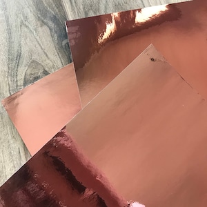 Sheets of rose gold adhesive mirror vinyl displayed to show the reflective chrome finish