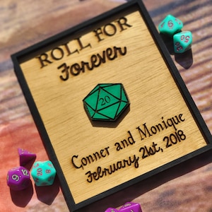 May include: A wooden sign with black trim reads "ROLL FOR Forever" with a green 20-sided die in the center. Below the die, the sign reads "Conner and Monique February 21st, 2018".  The sign is surrounded by green and purple dice.