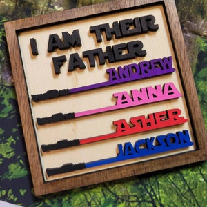 May include: Wooden sign with the text "I am their father" and the names Andrew, Anna, Asher, and Jackson written in different colors below.