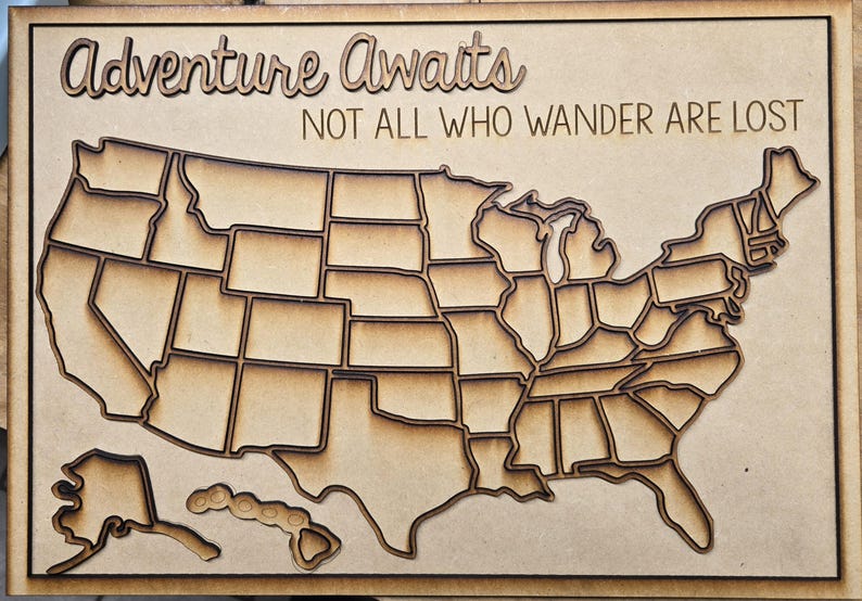 Puede incluir: Arte de pared de madera con un mapa detallado de los Estados Unidos, con cada estado cortado individualmente. Las palabras "Adventure Awaits" y "Not All Who Wander Are Lost" est&aacute;n cortadas con l&aacute;ser sobre el mapa. Hecho de madera marr&oacute;n claro.
