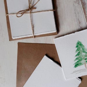 K&ouml;nnte beinhalten: Ein Satz leerer Karten mit braunen Papiert&uuml;ten, die mit Schnur zusammengebunden sind. Die Karten haben eine raue, handgemachte Textur und sind perfekt zum Schreiben von Notizen oder zum Erstellen von Einladungen.