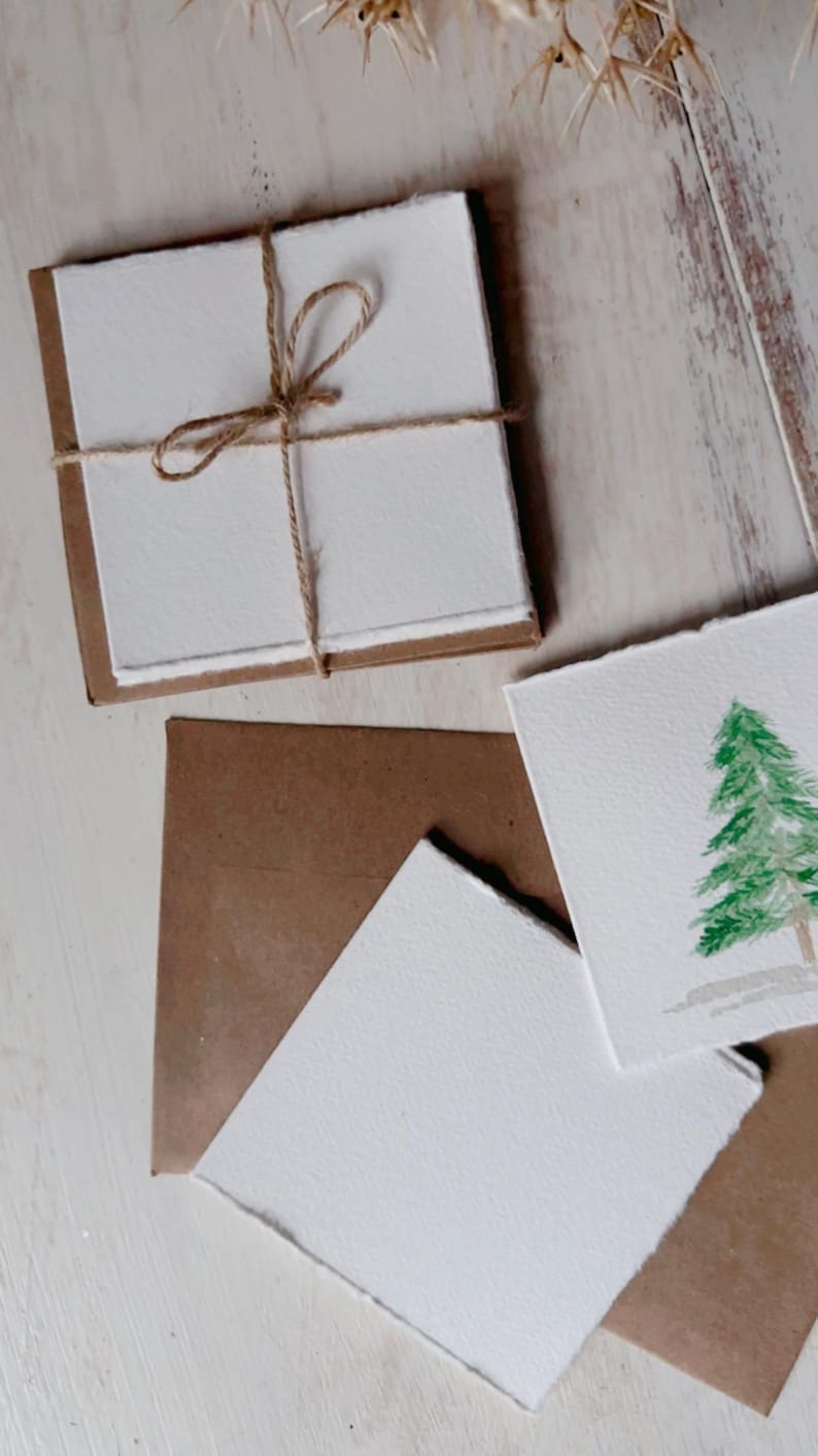 K&ouml;nnte beinhalten: Ein Satz leerer Karten mit braunen Papiert&uuml;ten, die mit Schnur zusammengebunden sind. Die Karten haben eine raue, handgemachte Textur und sind perfekt zum Schreiben von Notizen oder zum Erstellen von Einladungen.