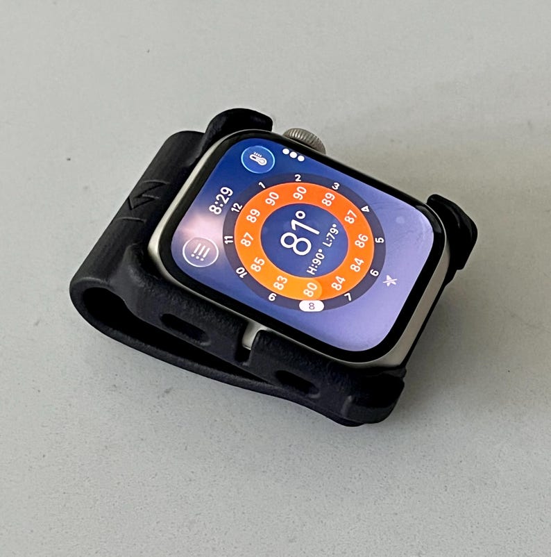 May include: A silver smartwatch encased in a black protective silicone bumper frame. The watch face displays a digital interface with a circular temperature gauge showing 81 degrees, a time of 8:29, and various weather-related data points.