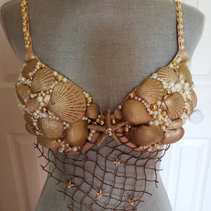 May include: A gold and white seashell bra with a brown fishnet bottom and gold starfish accents.