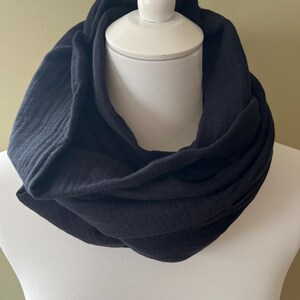 Peut inclure: Une &eacute;charpe noire en tissu doux et textur&eacute;. L'&eacute;charpe est pli&eacute;e et pr&eacute;sent&eacute;e sur un mannequin blanc.