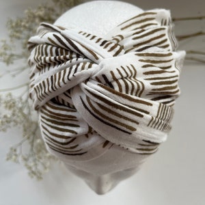 May include: White turban headband with a brown and white striped pattern.