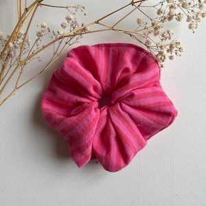 Könnte beinhalten: Ein pink-weiß gestreiftes Stoff-Haargummi.
