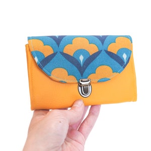 Die Damenhandtasche Paola besteht aus senfgelbem Kunstleder und türkisblauem Retro-Stoff