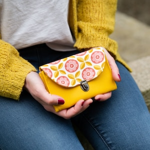 An der Damenhandtasche Charlie sind eine gelbe Kunstledertasche und ein rosa-gelber Retro-Stoff befestigt