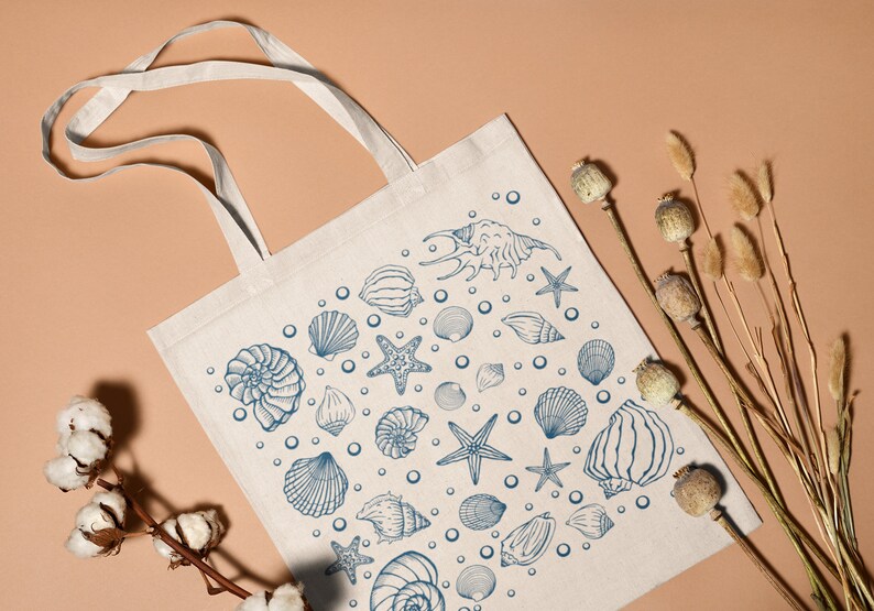 May include: A white canvas tote bag with blue illustrations of seashells, starfish, and bubbles. The bag has two handles.