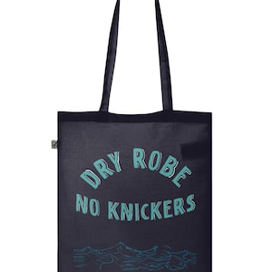 Op de afbeelding: Een donkerblauwe tote bag met de tekst "DRY ROBE NO KNICKERS" in turquoise groene letters. De tas heeft een golf- en bergontwerp aan de onderkant.