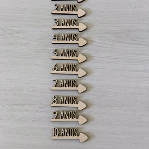 Peut inclure: Dix fl&egrave;ches en bois avec les chiffres de 1 &agrave; 10 et le mot "ANOS" (portugais pour "ann&eacute;es") sur chaque fl&egrave;che.