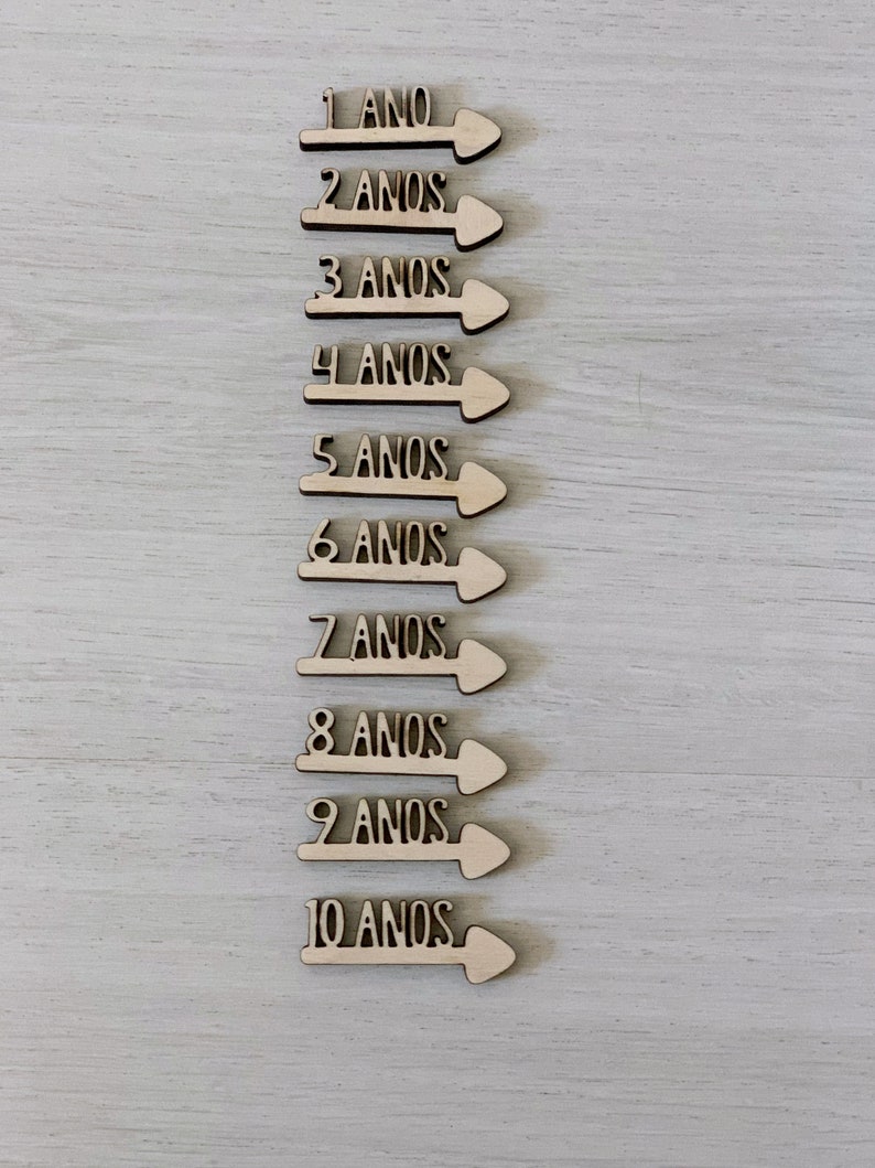 Peut inclure: Dix fl&egrave;ches en bois avec les chiffres de 1 &agrave; 10 et le mot "ANOS" (portugais pour "ann&eacute;es") sur chaque fl&egrave;che.