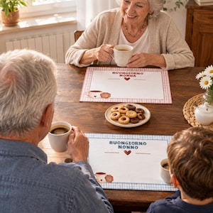 Op de afbeelding: Twee rechthoekige placemats met een geruite rand en een centrale afbeelding. De ene heeft een rode rand met de tekst "BUONGIORNO NONNA" en een hartje, de andere een blauwe rand met de tekst "BUONGIORNO NONNO" en een hartje.