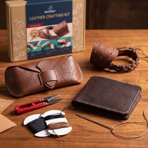 Könnte beinhalten: Ein Lederbastelset mit der Aufschrift BeaverCraft Leather Crafting Kit, bestehend aus einem braunen Lederbrillenetui, einer geflochtenen Lederstulpe, einer braunen Geldbörse mit Geldsackmotiv, einer roten Schere und zwei Garnrollen.