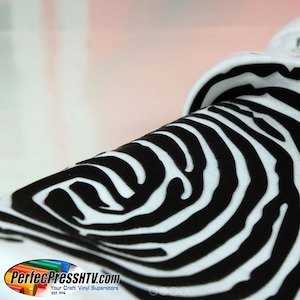 May include: Close-up of a white fabric with a black fingerprint design. The fabric is folded over, showing the texture of the design.