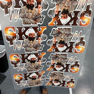 May include: Four sheets of stickers with a man wearing a leopard print shirt and a white cowboy hat. The stickers feature the text "Sky Whatley" and "Happy Mother's Day" in a gold and brown color scheme.