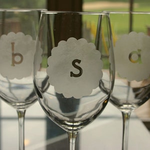 Puede incluir: Tres copas de vino de vidrio transparente con las letras 'b', 's' y 'a' grabadas en la parte delantera. Las copas est&aacute;n sobre una superficie blanca.