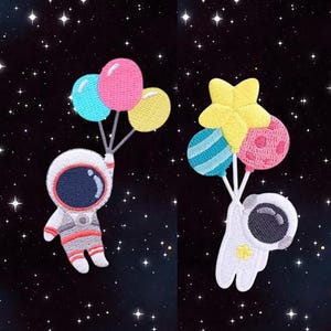 May include: Two embroidered patches of astronauts in space holding balloons. One astronaut is holding a star-shaped balloon and the other is holding a cluster of colourful balloons.