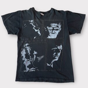 May include: Black t-shirt with a white print of the band Bauhaus. The print features four black and white images of the band members.