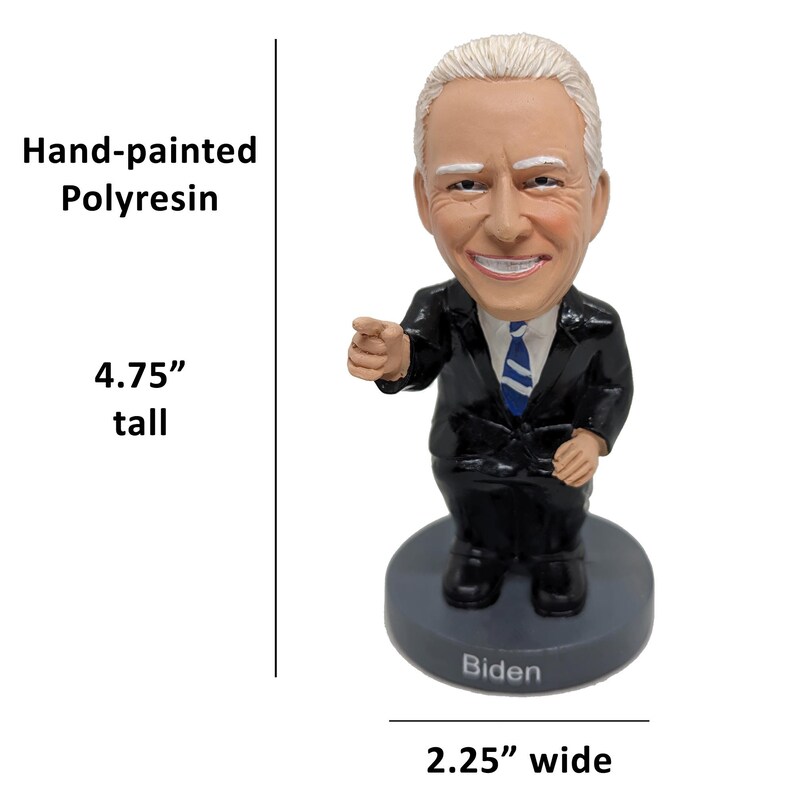 May include: Hand-painted polyresin figurine of a person with a smiling face, wearing a black suit and blue tie. The figurine is 4.75 inches tall and 2.25 inches wide. The base of the figurine is gray and has the word "Biden" written on it.