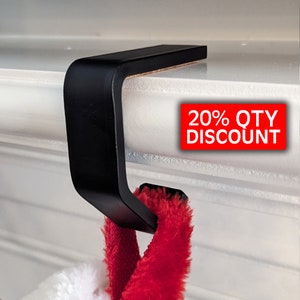May include: Black metal stocking holder for hanging stockings on a mantelpiece. The holder is attached to the mantel with adhesive.