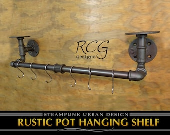 Pode incluir: Prateleira rústica para pendurar panelas feita de tubo de ferro preto com uma prateleira em cada extremidade e ganchos para pendurar panelas. A prateleira é etiquetada "STEAMPUNK URBAN DESIGN RUSTIC POT HANGING SHELF".