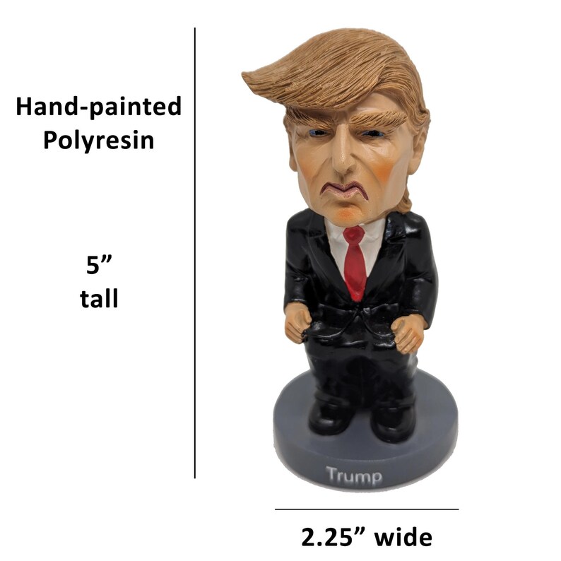 May include: Hand-painted polyresin figurine of a person with blonde hair wearing a black suit and red tie. The figurine is 5 inches tall and 2.25 inches wide. The base of the figurine is gray and has the word "Trump" printed on it.