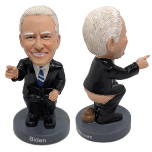 May include: A bobblehead figurine of a person in a black suit and tie. The figurine is in two poses, one standing with a hand pointing forward and the other sitting with the back of the suit pulled down. The base of the figurine is gray and has the word "Biden" printed on it.