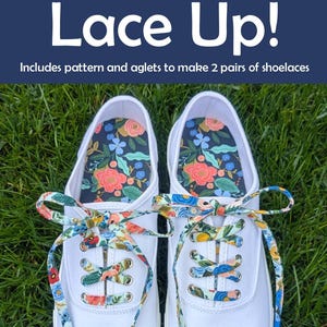 May include: White canvas sneakers with floral patterned insoles and colorful shoelaces. The laces and insoles feature a mix of flowers and leaves. The text "Lace Up!" is at the top of the image.