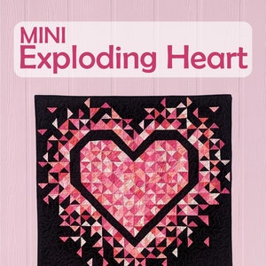The Mini Exploding Heart quilt pattern cover with an all pink heart with a black background fabric hanging on a light pink wall