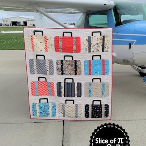 Può includere: Una trapunta con un design a patchwork di valigie in vari colori e motivi. La trapunta è esposta davanti a un piccolo aereo. La trapunta è intitolata "Suitcases" e la parte inferiore della trapunta ha un logo che dice "Slice of Pi Quilts".
