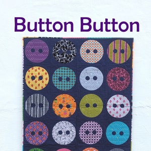 May include: A quilt with a navy blue background and 18 colorful button-shaped patches. Each patch has a different design, including polka dots, stripes, and scissors. The quilt is titled "Button Button" and is made by "Slice of Pi Quilts".