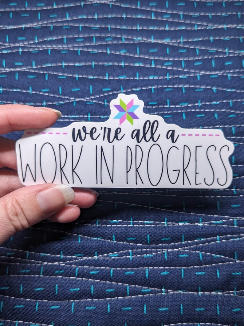 Quilt sticker with phrase "we're all a work in progress"