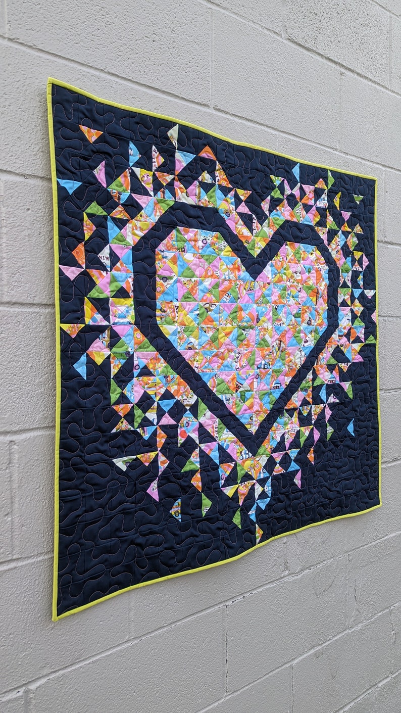 A Mini Exploding Heart quilt made with colorful fabrics and a navy background fabric