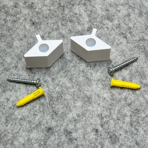 May include: Two white plastic wall anchors with a screw hole in the center, two yellow plastic wall anchors, and two silver screws.