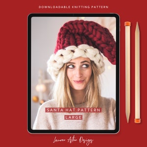 May include: A digital tablet displaying a knitting pattern for a large Santa hat. The pattern is titled "Santa Hat Pattern Large" and is by "Lauren Aston Designs". The image shows a woman wearing the hat, which is red and white.