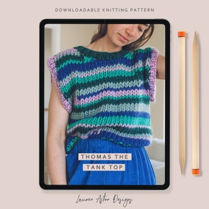 May include: A digital image displays a colorful, striped knitted tank top labeled "Thomas the Tank Top." The top features horizontal stripes in shades of green, blue, and purple. Two wooden knitting needles with orange tips are positioned to the right of the tablet.