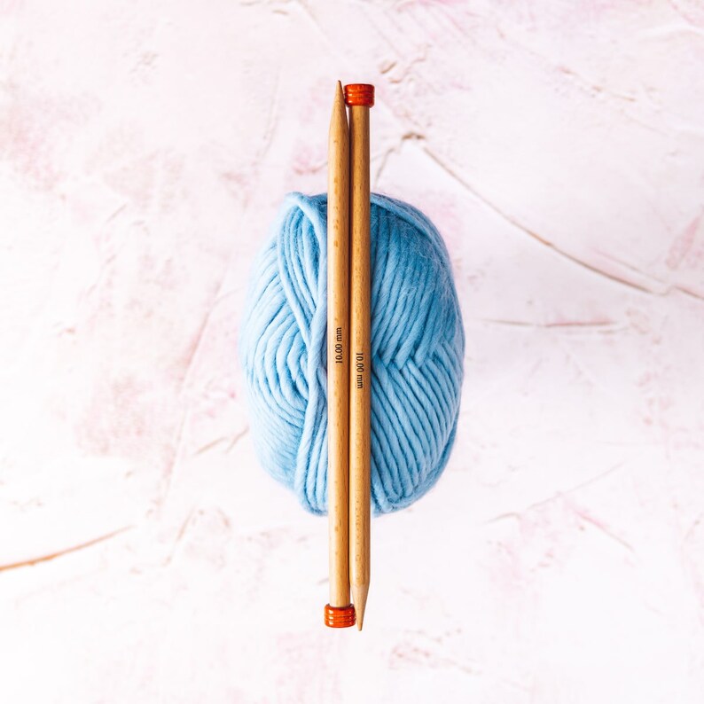 May include: A ball of light blue yarn with two wooden knitting needles, each marked "10.00 mm", sticking through the center.