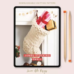 May include: A digital tablet screen displays a downloadable knitting pattern for a cream-colored chunky knit stocking. The text reads DOWNLOADABLE KNITTING PATTERN, JUMBO STOCKING, and SMALL. Two wooden knitting needles are placed beside the tablet.