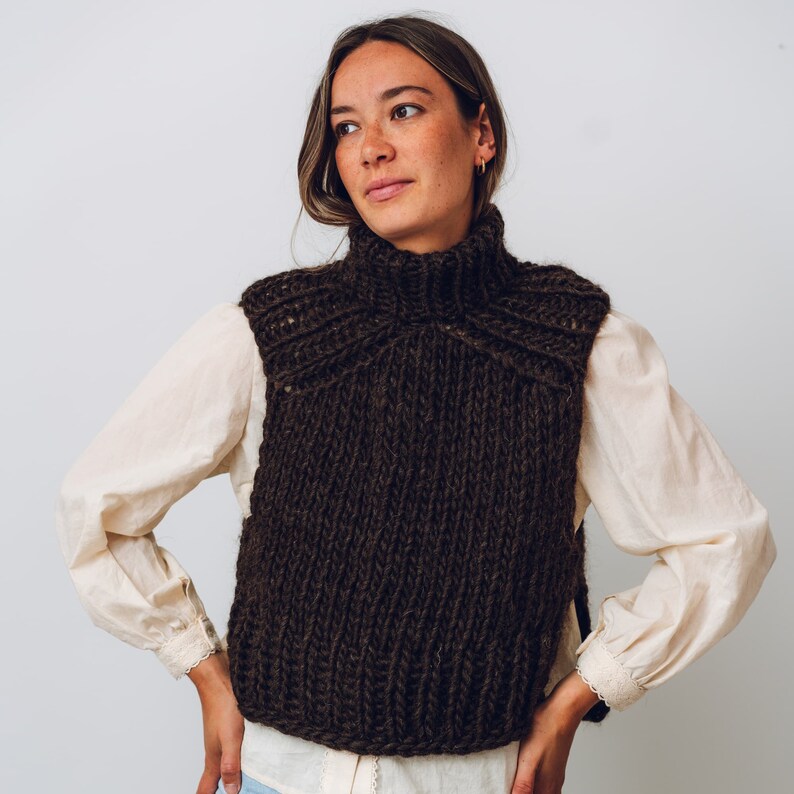 K&ouml;nnte beinhalten: Eine braune Strickweste mit Rollkragen und hohem Kragen. Die Weste ist aus einem dicken Garn gefertigt und hat eine lockere Passform.