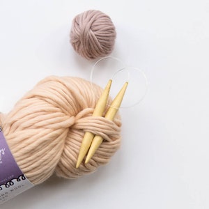 May include: A ball of pale pink yarn with two wooden knitting needles and a clear plastic stitch marker.